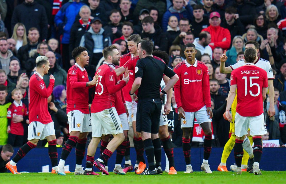 Manchester United's players surround the referee asking for a penalty