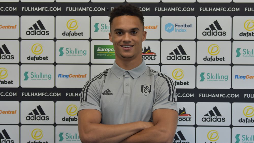 Antonee Robinson folds his arms in front of sponsorship backdrop