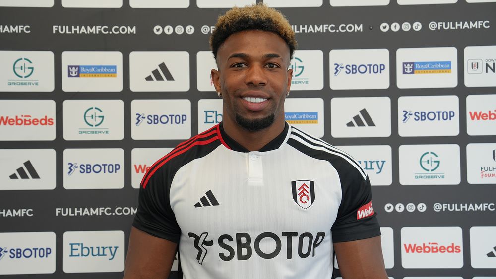 Adama Traoré poses in front of the sponsors board