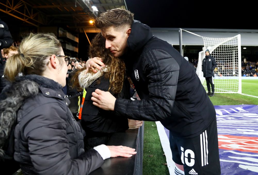 Tom Cairney hugs Clare Parish's daughter after Fulham's match against Millwall