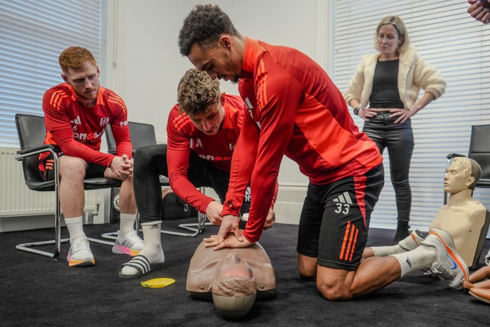 Antonee Robinson delivers chest compressions to a dummy during CPR training